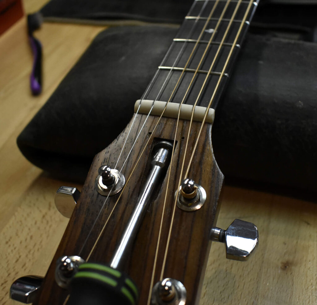 Image showing an acoustic guitar truss rod being adjusted with a truss rod wrench