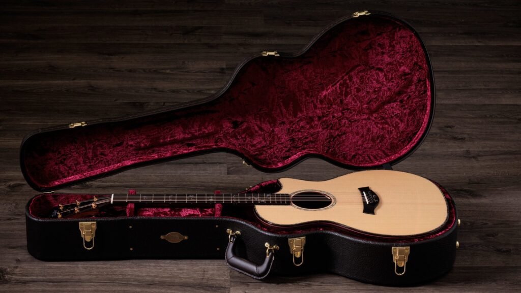 A Taylor Legacy 914ce acoustic-electric guitar laying in its deluxe hardshell guitar case with maroon velvet interior