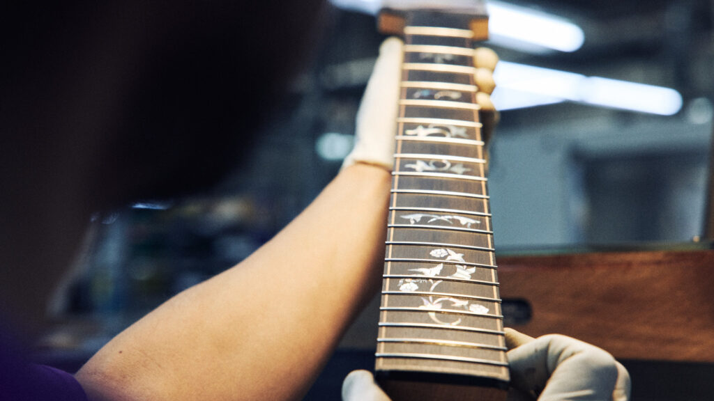An ebony fretboard for a Taylor acoustic guitar with abalone inlays