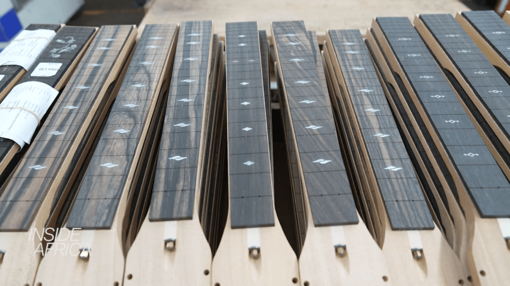 An array of acoustic guitar fretboards made from ebony with intricate inlays on a wooden table